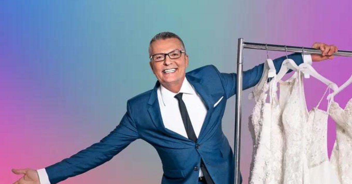 Randy Fenoli poses with a rack of wedding dresses